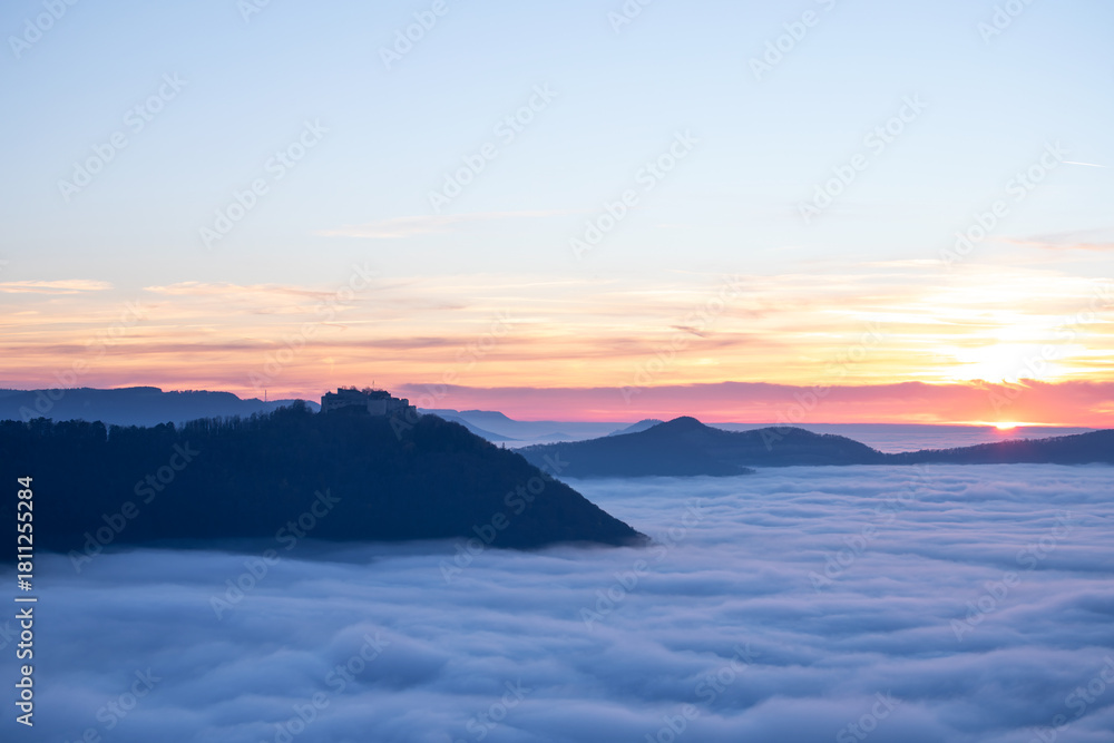 Fototapeta premium Sonnenuntergang über dem Nebelmeer vom Beurener Fels zur Burg Hohenneuffen, Schwäbische Alb, Baden-Württemberg, Deutschland.