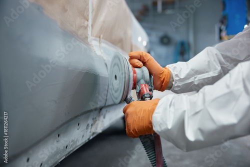 Technician sanding car body panel with orbital sander