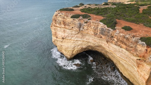 Rocky coastal cliff with natural arch in Faro, Algarve, Portugal