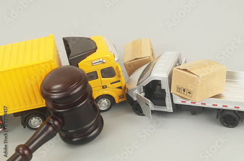Judge gavel and container carrier hits truck on grey background. Legal proceeding traffic accident concept.