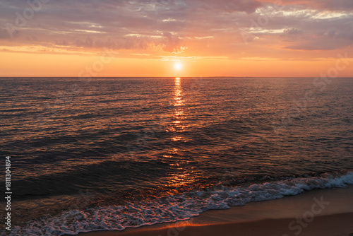 Fototapeta Naklejka Na Ścianę i Meble -  Scenic golden sunset over the Baltic Sea in Estonia featuring a dramatic orange sky and gentle waves on a sandy beach