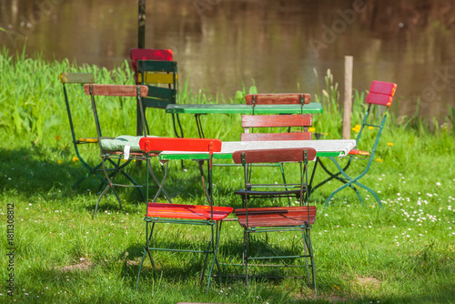 Fototapeta Naklejka Na Ścianę i Meble -  Bunte Stühle und Tische eines Cafes auf einer Rasenfläche an einem Fluss, Gastronomie, Deutschland, Europa