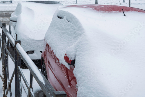 Parked cars lie buried under deep winter snow, capturing a quiet moment of heavy snowfall and seasonal urban stillness in morning light.