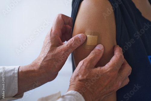 Doctor applying adhesive bandage on arm after vaccination at hospital