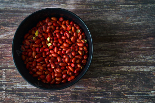 Bowl of organic peanuts on rustic table viewed from above