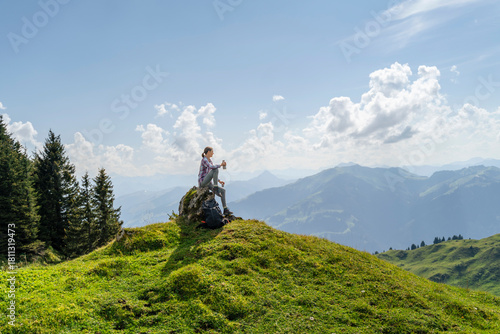 Mature woman sitting on rock at mountain under cloudy sky