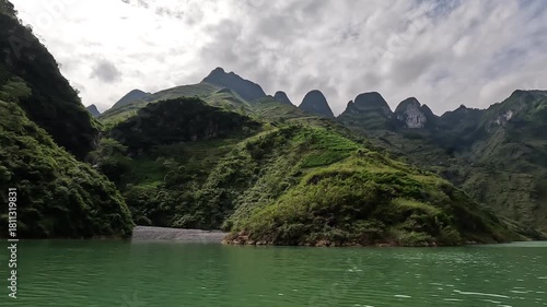 The Nho Que River flows between steep karst mountains in Ha Giang, Vietnam. Turquoise water, narrow canyon walls, and dramatic scenery create a stunning and immersive travel footage.