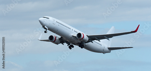 Airplane take off on the blue sky, with white clouds. Aircraft flying on sky background. White passenger jet plane in the blue sky. Low angle view of Airplane flying under blue sky, with white clouds