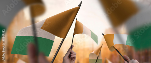 Cote dIvoire flags in their hands on a blurred urban background