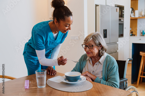 Nurse feeding senior woman at home with care and companionship