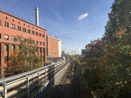 Berlin Germany October 2025 Industrial red brick building and tree lined rail cutting under blue sky