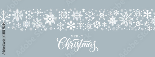 Horizontal Christmas banner with a border of white snowflakes along the top and "Merry Christmas" script calligraphy below, set on a muted light blue/gray background. Winter vector design template for
