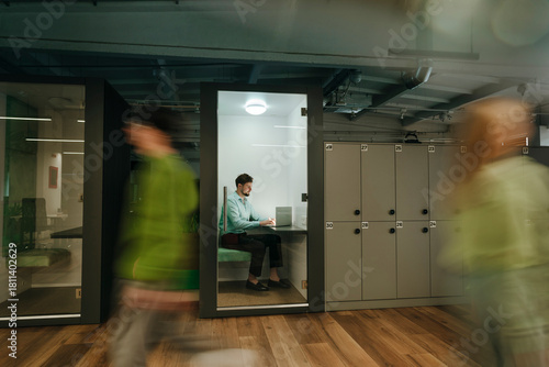 Businessman working on laptop in modern office cubicle with motion blur