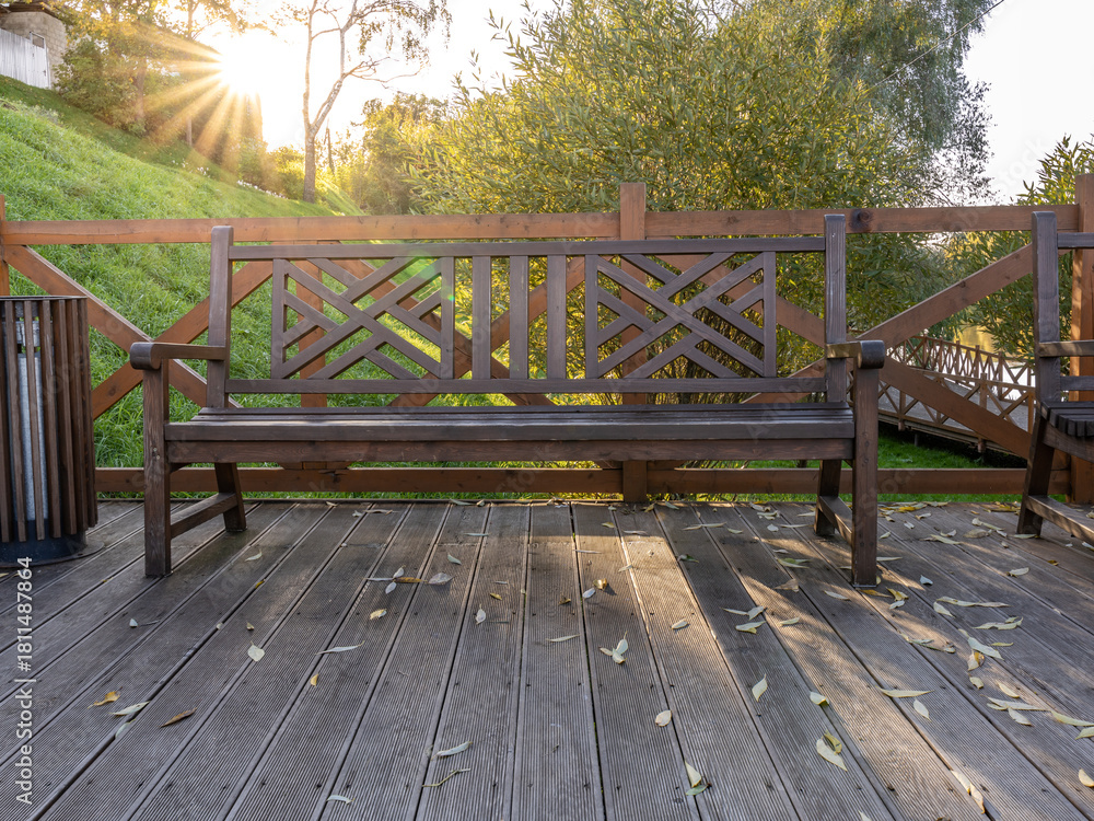 Fototapeta premium Wooden bench sits on a wooden deck overlooking a grassy hill