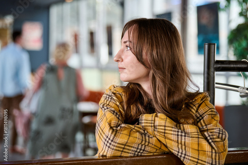 Wallpaper Mural Young woman in yellow plaid shirt sitting indoors looking thoughtful Torontodigital.ca
