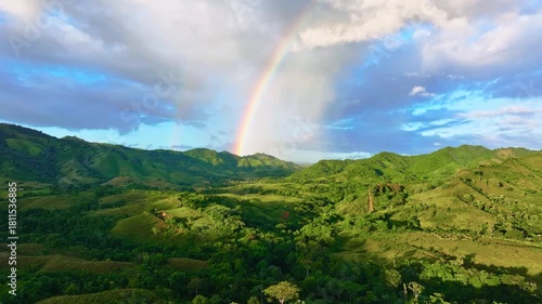 Panoramic view of the mountains through a rainbow on a sunny summer day. Aerial view of a green mountain pass during rain. Natural landscape and tourist destination in Latin America in summer.