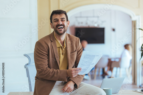 Confident Businessman Laughing While Holding Documents in Modern Office During Meeting Break