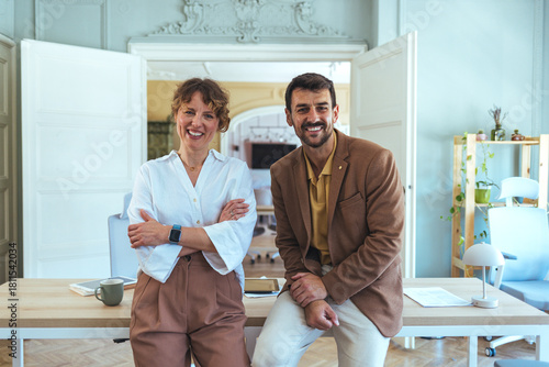 Friendly Team Of Two Colleagues In A Modern Office Smiling At The Desk