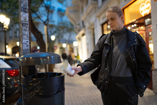 Woman disposing of cup in city trash