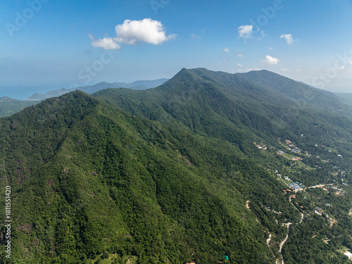 Vast mountain range with thick green vegetation stretching to the horizon, set against a bright blue sky. Ko Pha Ngan, Thailand.