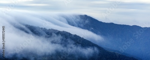 Принти на полотні clouds spilling over the mountain ridge blue colored