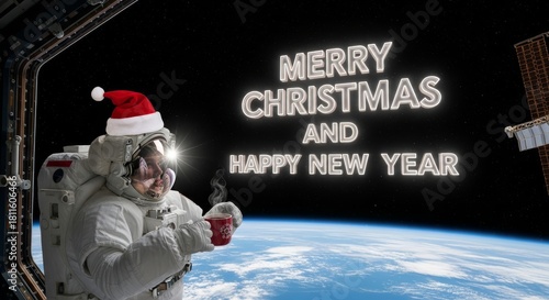 Fototapeta Naklejka Na Ścianę i Meble -  Festive Greetings from Space - Astronaut in spacesuit and Santa hat celebrates Christmas and New Year aboard the space station with a cup of hot drink overlooking Earth