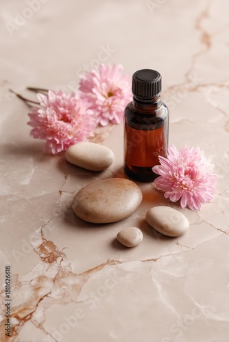 A calming arrangement of smooth massage stones, an amber oil bottle, and pink flowers on a marble surface