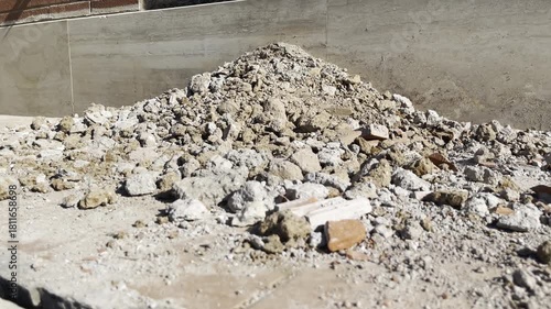 Broken concrete and rubble on the ground near the building wall left after demolition, dusty cement trash on construction site, building repairing and improvement concept