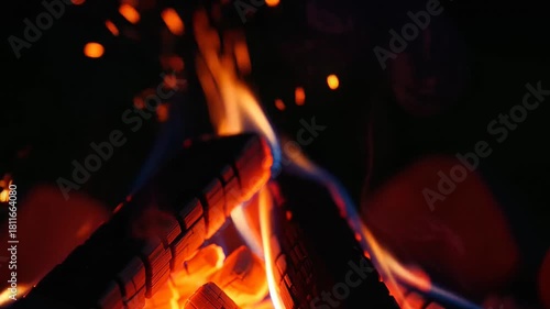 Campfire flames at night with glowing embers creating warmth ambiance