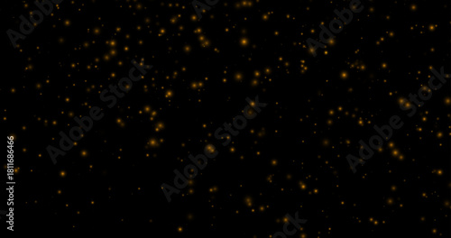 Golden dust particles of various sizes and transparency on a black background. Abstract glowing effect with a warm, festive atmosphere.