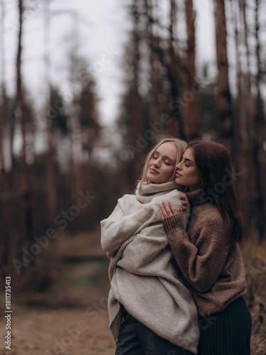 Young lesbian couple embracing side view with closed eyes in forest