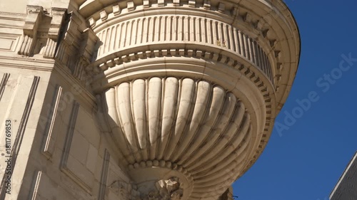 Beautiful limestone building facade in France, architectural element under the corner balcony