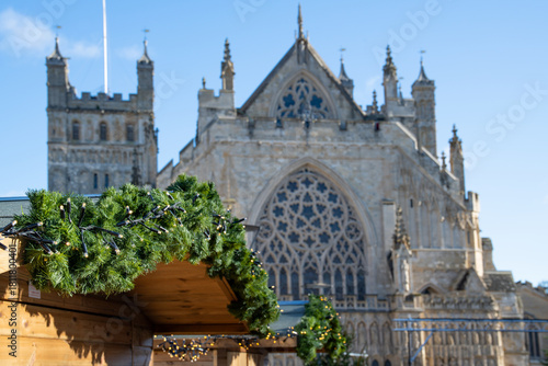 Christmas market on Exeter Cathedral green. Green Christmas spruce with Exeter cathedral behind. Festive celebration.