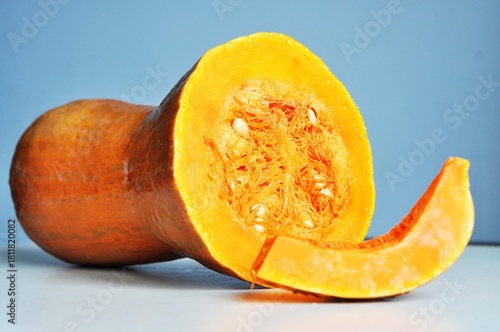 A juicy slice of pumpkin with bright orange flesh and seeds on a light background.