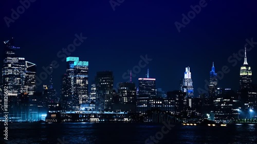 Wallpaper Mural Long cruise boat moves by the East River near the Pier 55. Luminous skyline of New York at nighttime at backdrop. Torontodigital.ca