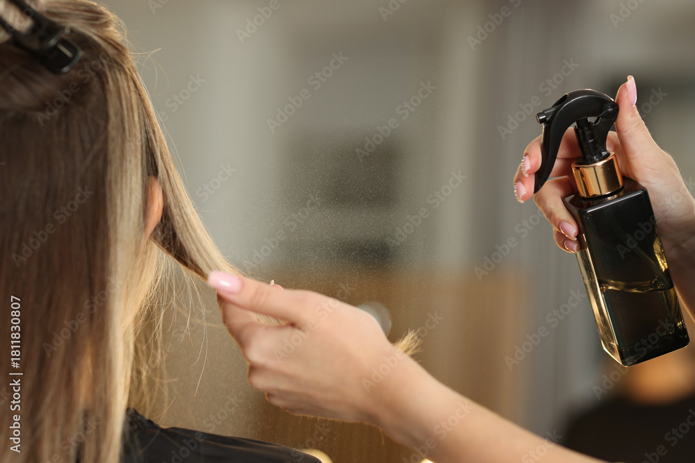 Fototapeta premium Hairdresser spraying woman's hair before haircut in salon, closeup
