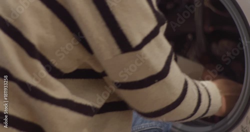 Close up of a young woman  removing clothes from laundry machine