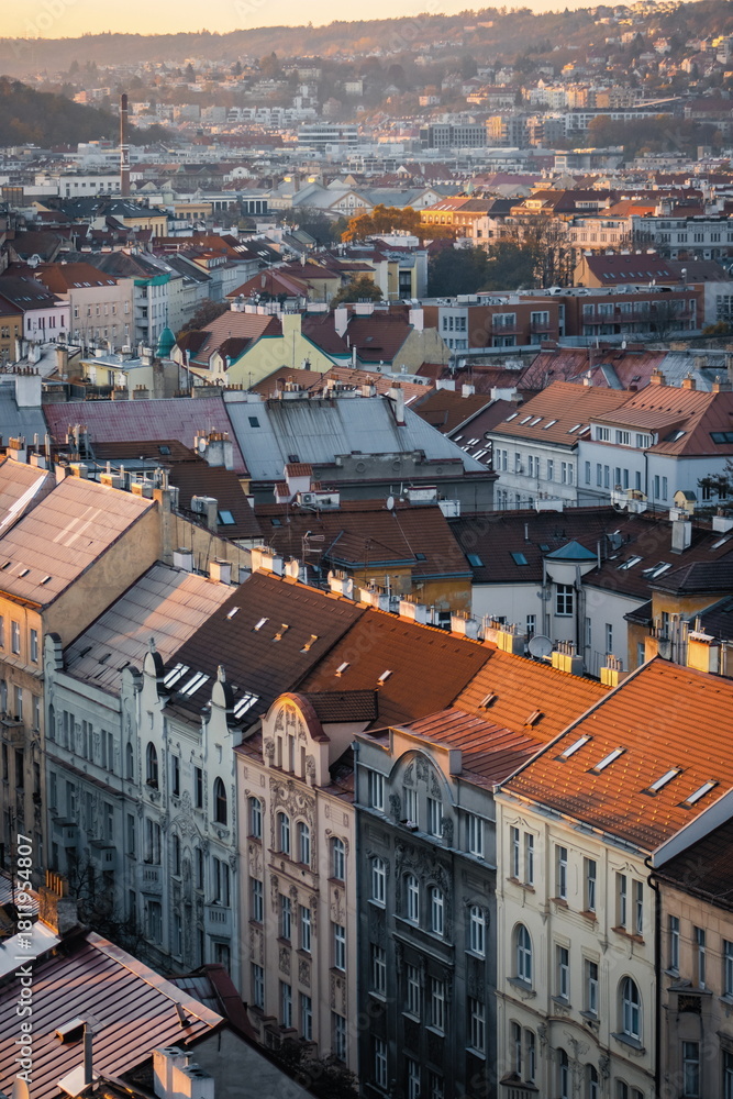 Obraz premium Warm evening light casting over the historic rooftops of Prague, captured from Nusle Bridge, revealing layers of charming architecture and autumn-tinted cityscape.