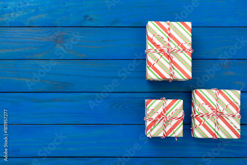 Striped Christmas gift boxes on wooden background, top view