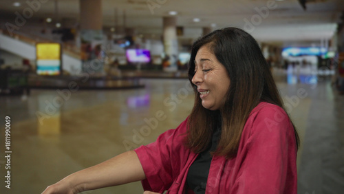 Hispanic middleaged woman pulls thick rope with left arm at bustling airport terminal; determination resolve focus.