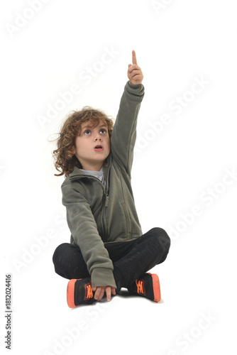 front view of  boy dressed in sportswear sitting on the floor pointing up on white background