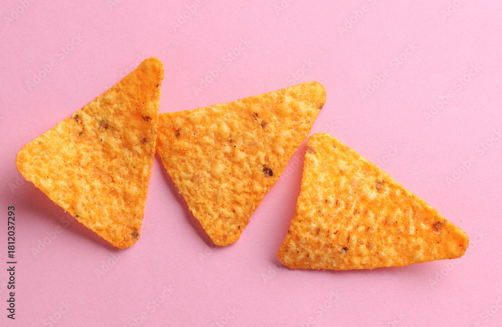 Fototapeta premium Triangular appetizing corn tortilla chips slices on pink background