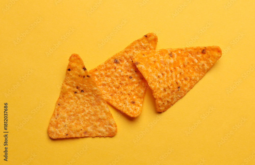Fototapeta premium Triangular appetizing corn tortilla chips slices on yellow background
