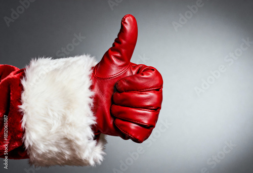 Santa Claus hand in red leather glove giving thumbs up gesture, symbol of approval and agreement, fun Christmas celebration