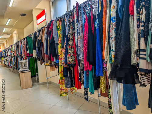 Photograph of colorful clothes hanging neatly on hangers in a second-hand store. Perfect image for illustrating sustainable fashion, recycling, and the concept of reusing garments to reduce waste.