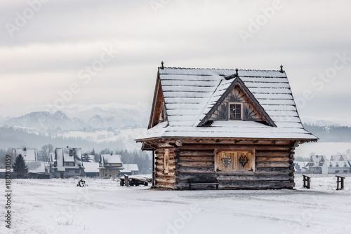 Fototapeta Naklejka Na Ścianę i Meble -  Wooden cabin in snowy landscape with mountains behind