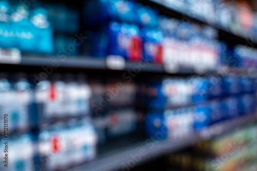 Blurred view of bottled beverages on market shelf.