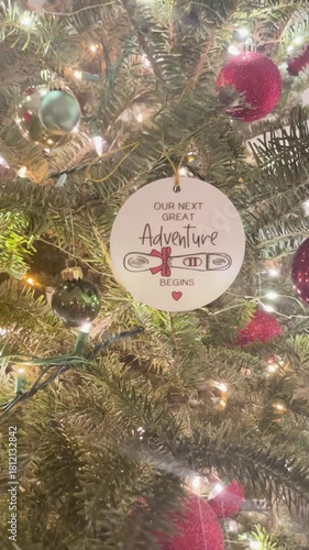 Close up Christmas tree ornament pregnancy announcement with twinkling lights, cozy festive home, emotional holiday family reveal scene