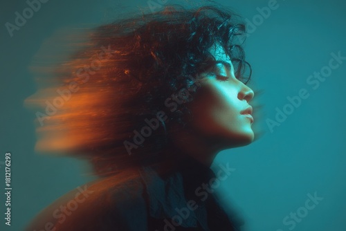 Stylized portrait of woman with curly hair and motion blur in warm orange and teal lighting