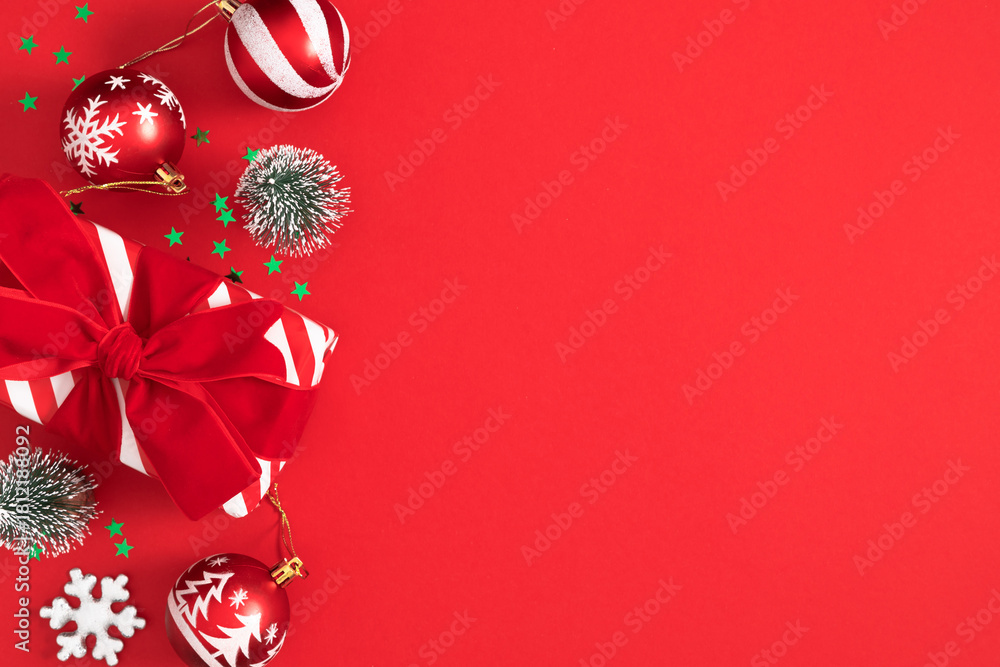 Obraz premium Festive Christmas composition with red and white balls, gift box and decor on a bright red background with space for text. Perfect for Christmas greetings and social media posts.
